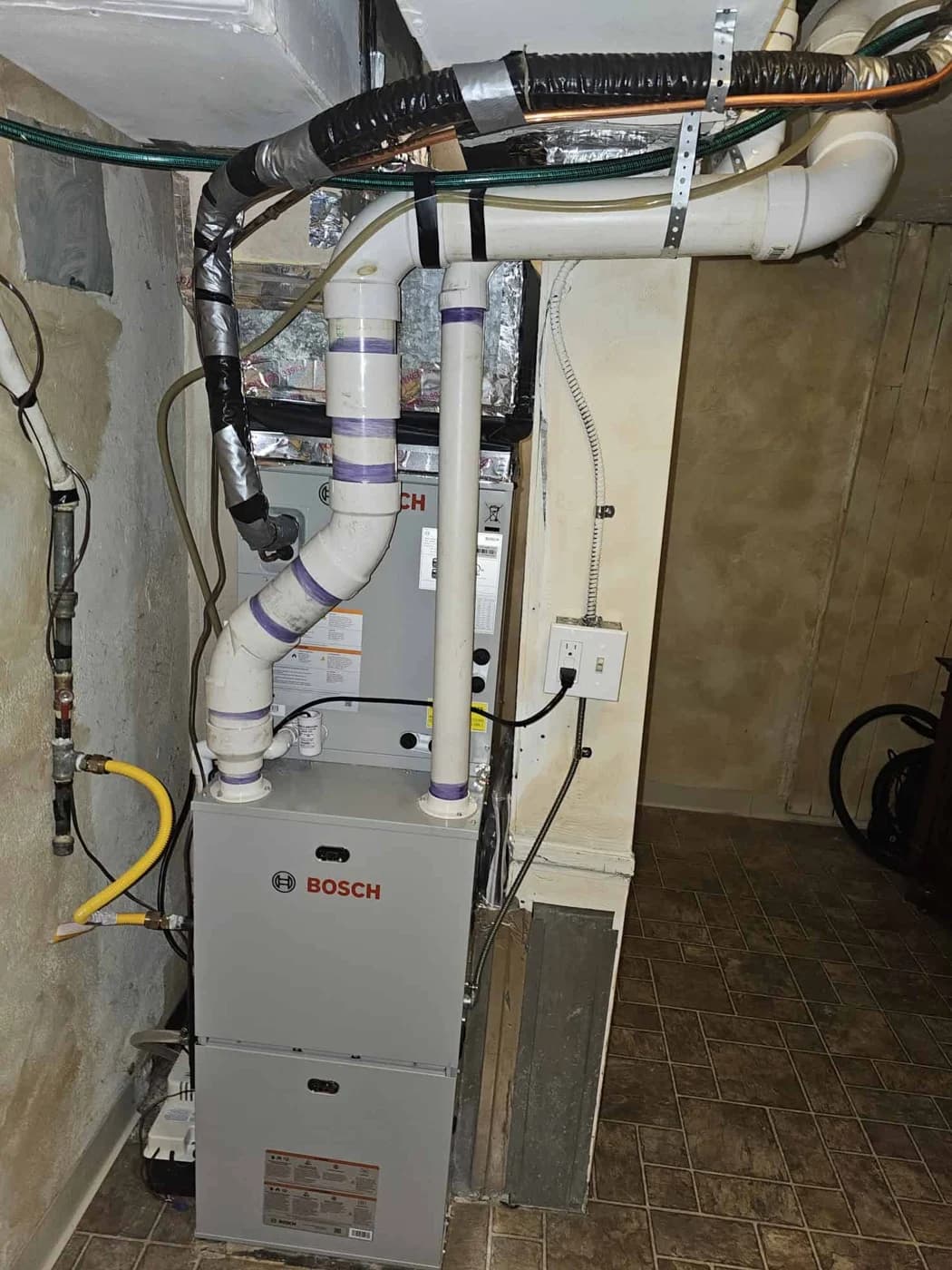 Bosch furnace and cased coil with white vent pipes and sheet metal ductwork